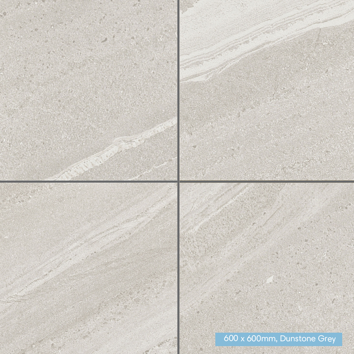 Four square floor tiles arranged in a 2x2 grid, showing a light warm gray stone-like surface with subtle veining. A small label in the bottom-right corner reads '600 x 600mm, Dunstone Grey'.