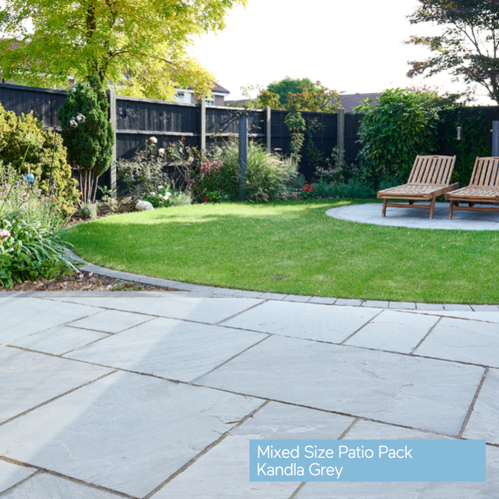 Patio with Kandla Grey paving stones, grass, and wooden chairs in a garden setting.